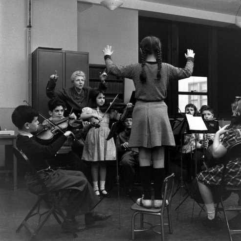 an old black and white photo of some people playing instruments in front of a group of children