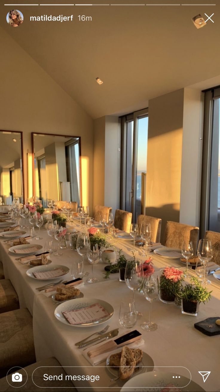 a long table is set up with wine glasses and place settings