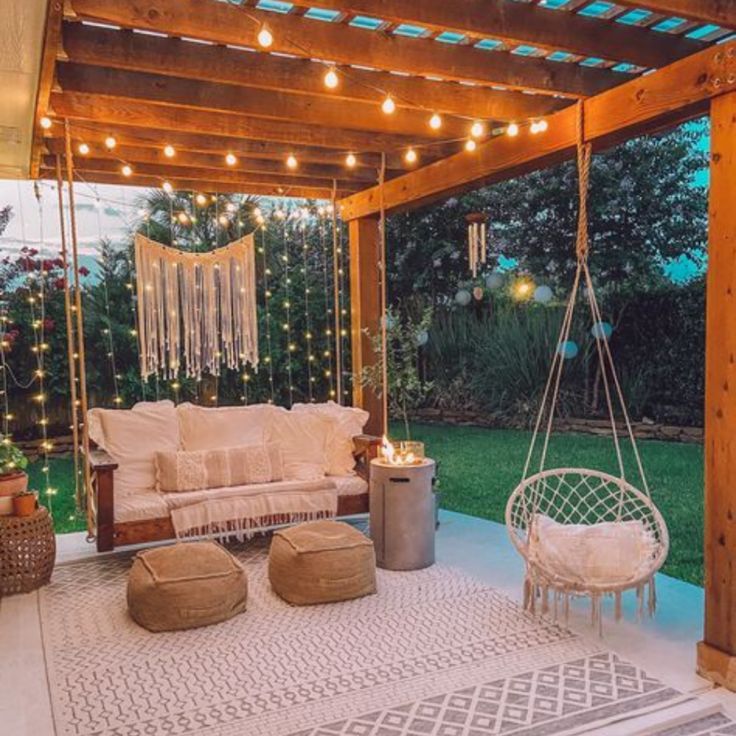 an outdoor living area is lit up with string lights and hanging furniture, including a swing chair