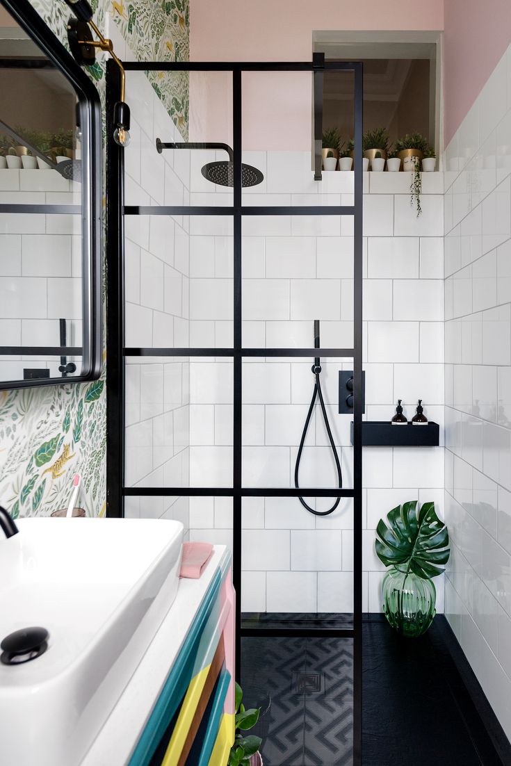 a bathroom with black and white tiles, pink walls, and a glass shower door