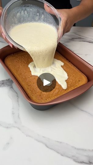 someone pouring batter on top of a cake in a pan with white icing over it