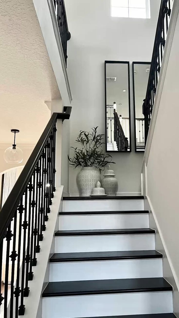 there is a vase with flowers on the bottom of this stair case and mirrors above it