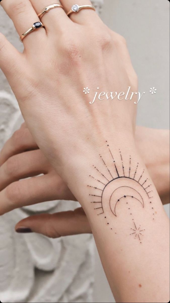 a woman's hand with a small sun and moon tattoo on her left wrist