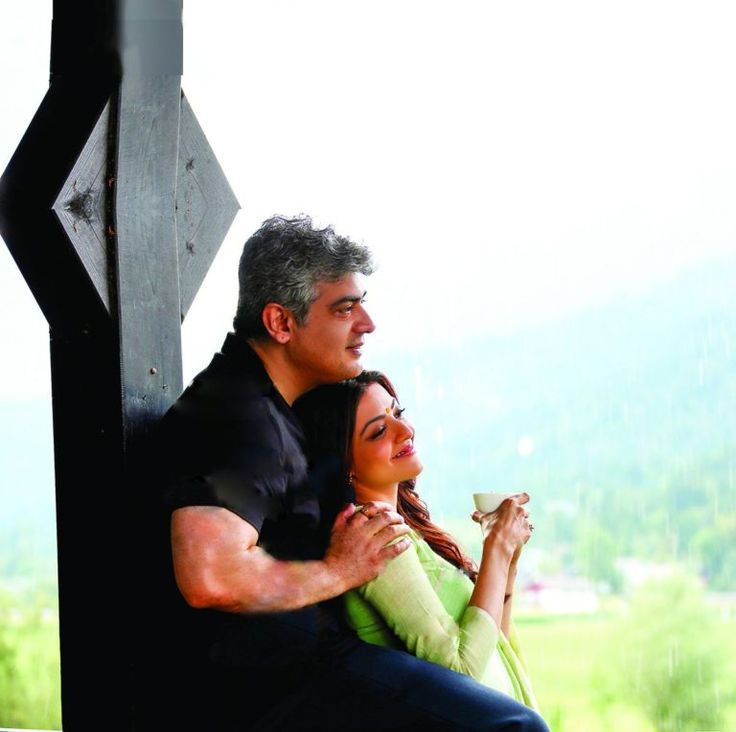 a man and woman sitting next to each other on a bench in front of a window