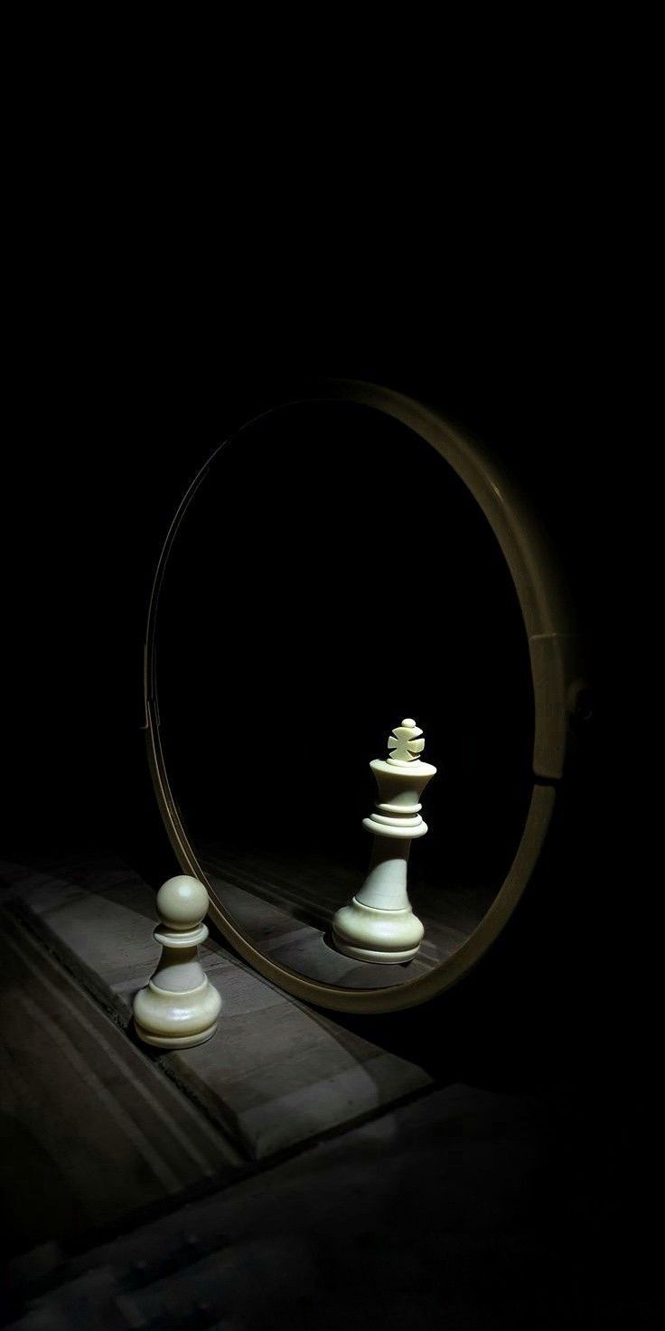 a mirror with some white chess pieces in front of it and the reflection of them