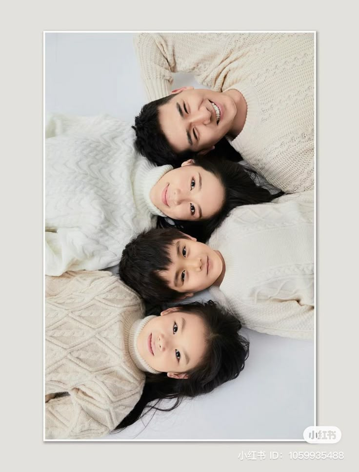 three women are smiling while laying on the floor in front of a white blanket and wearing sweaters