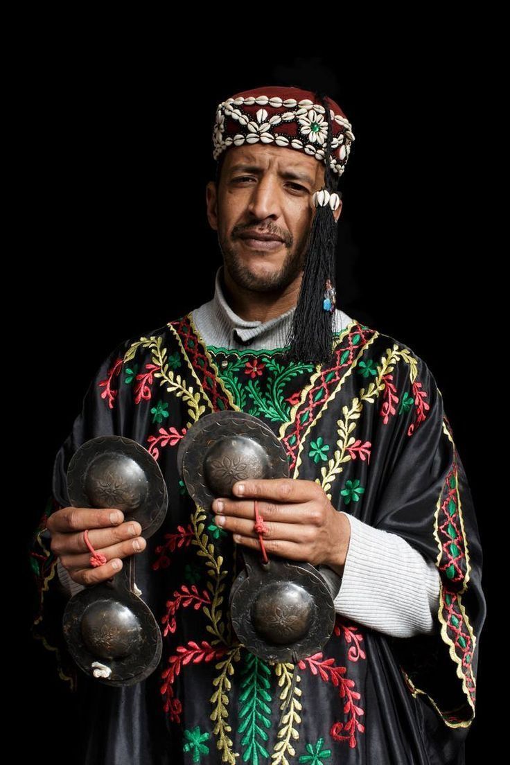 a man in an ethnic costume holding two bells