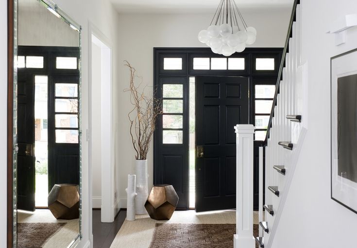 an entryway with black doors and white trim, carpeted flooring and decorative vases