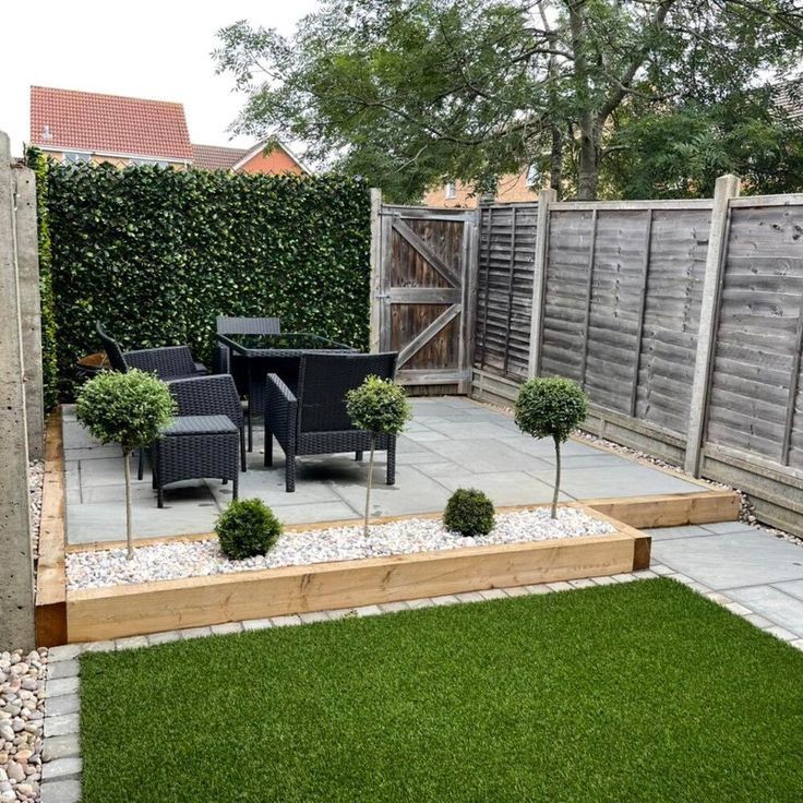 an outdoor patio with grass and small trees in the center, next to a wooden fence