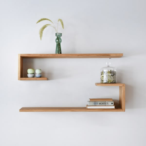 two wooden shelves with books and vases on them, one shelf has an egg in it