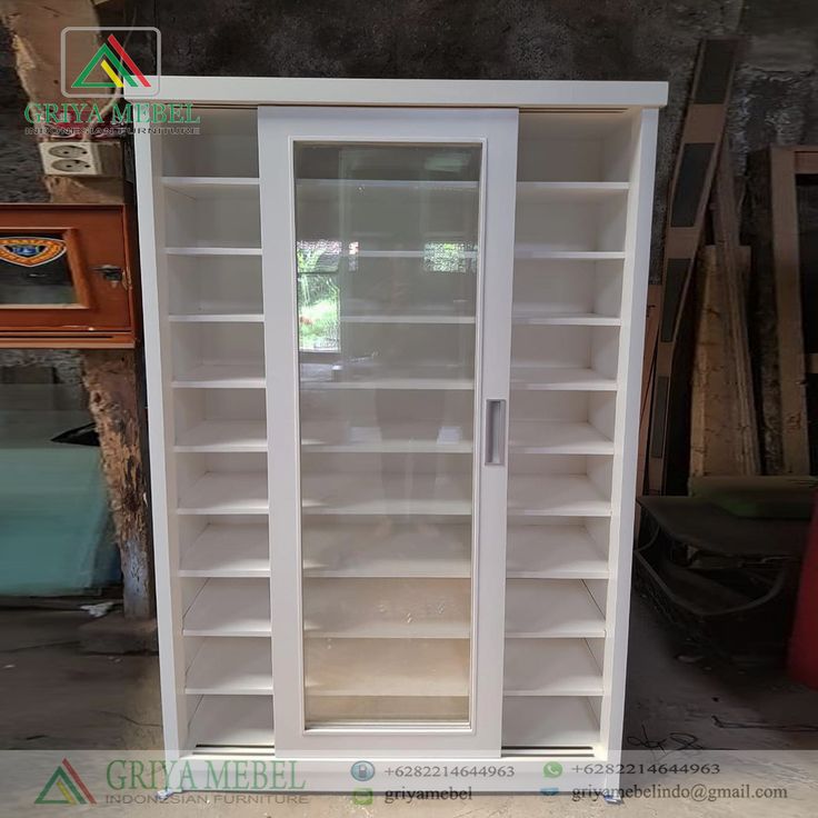 an empty white bookcase with glass doors in a room filled with other books and furniture