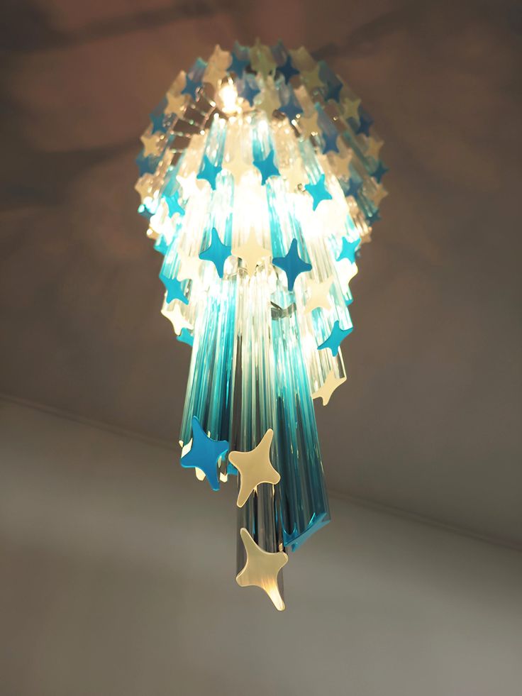 a chandelier with stars hanging from it's sides and lights on the ceiling