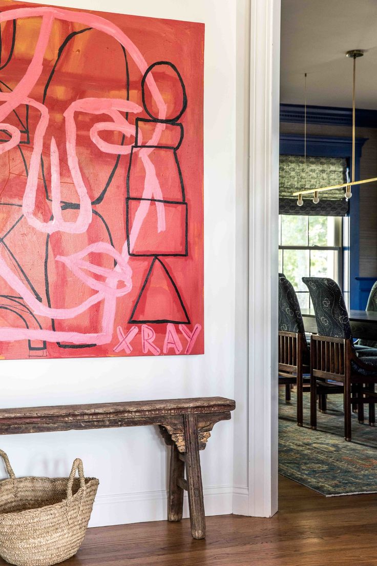 a painting is hanging on the wall next to a wooden bench in front of a dining room table