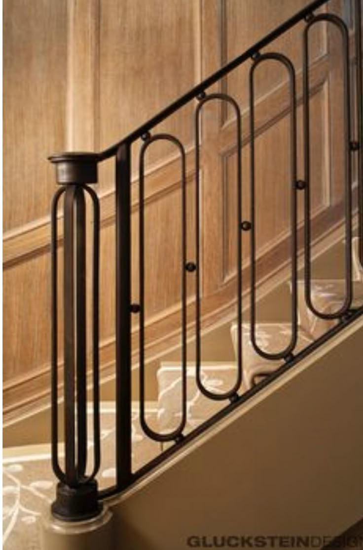 an iron handrail on the stairs leading up to a wood paneled wall and door