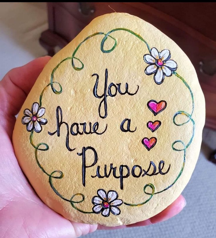 a hand holding a painted rock that says you have a purpose