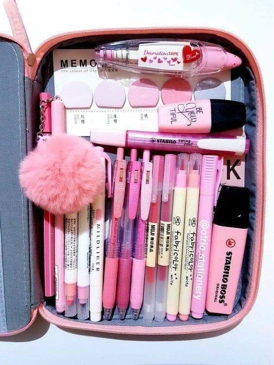 a pink case filled with lots of different types of pens and pencils on top of a white table