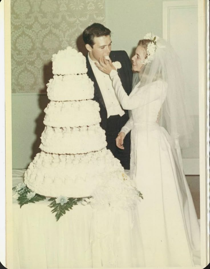 an old photo of a bride and groom feeding each other wedding cake at their reception