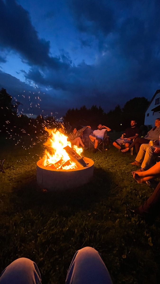 people sitting around a fire pit at night