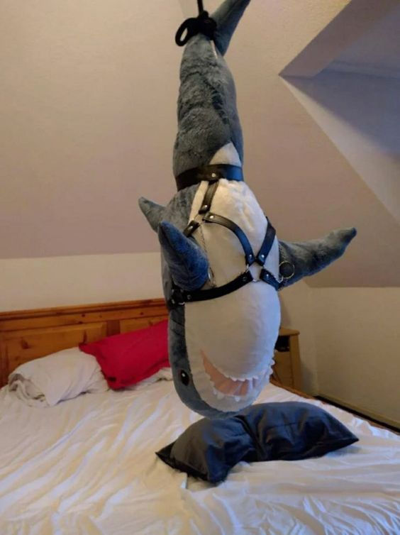 a stuffed animal on top of a bed with its head in the shape of a shark