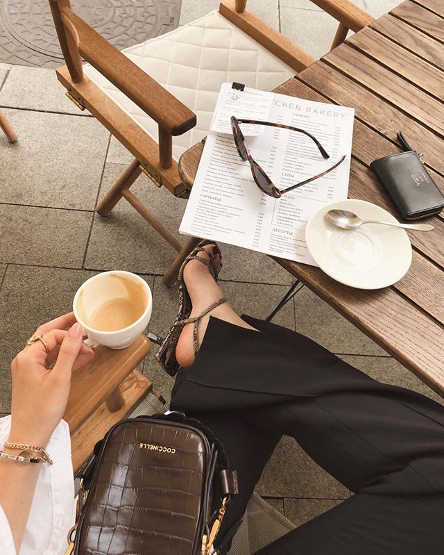 a woman sitting at a table with a cup of coffee