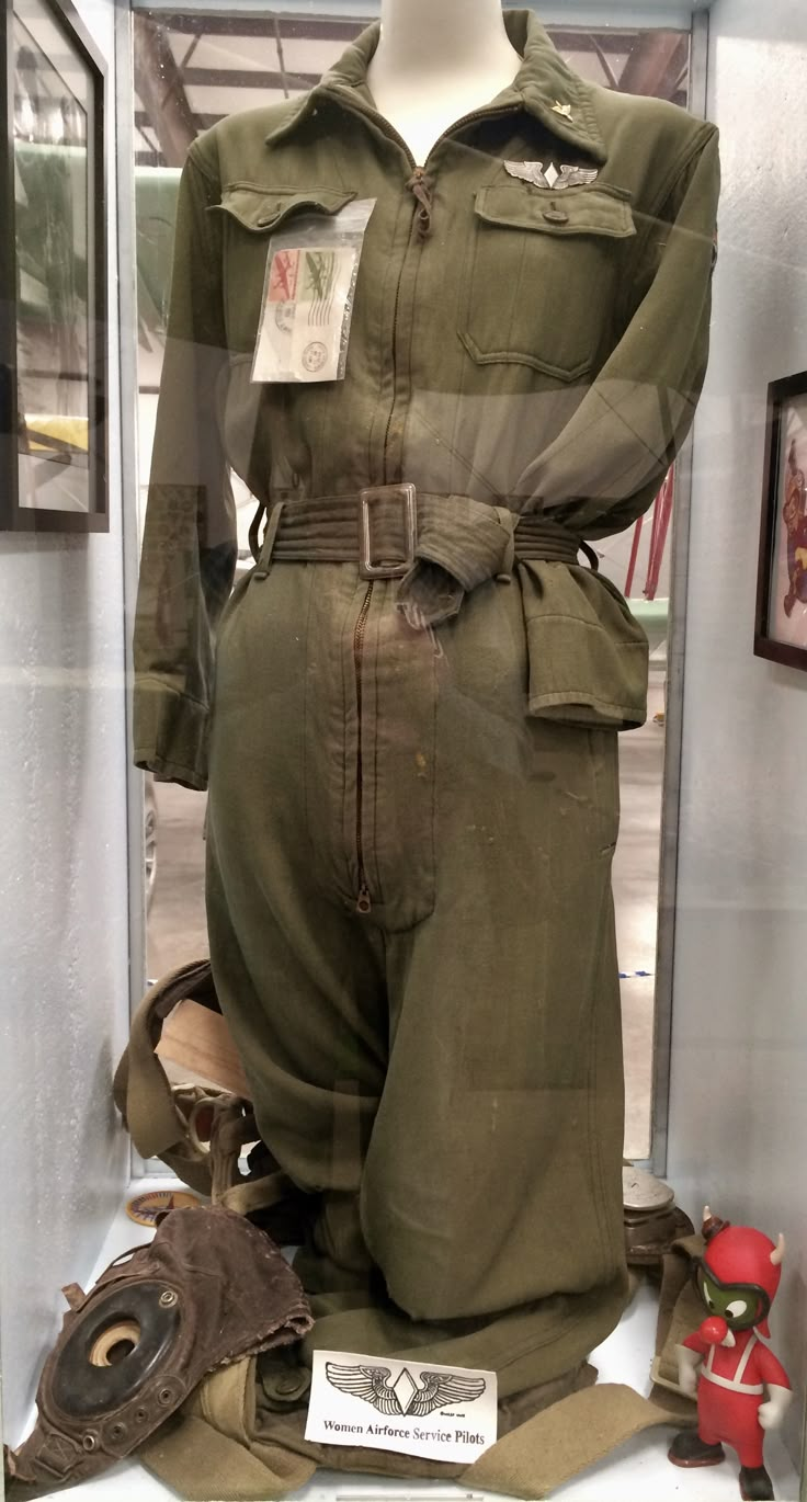 an army uniform is on display in a glass case with other items around the room