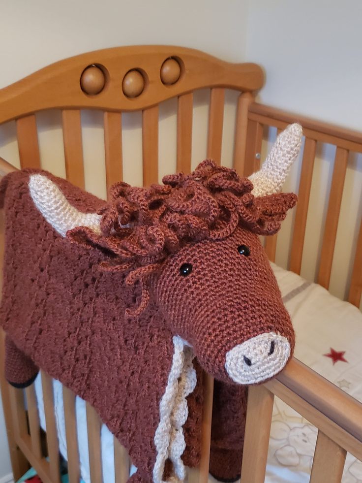 a crocheted cow blanket on top of a wooden crib in a child's room