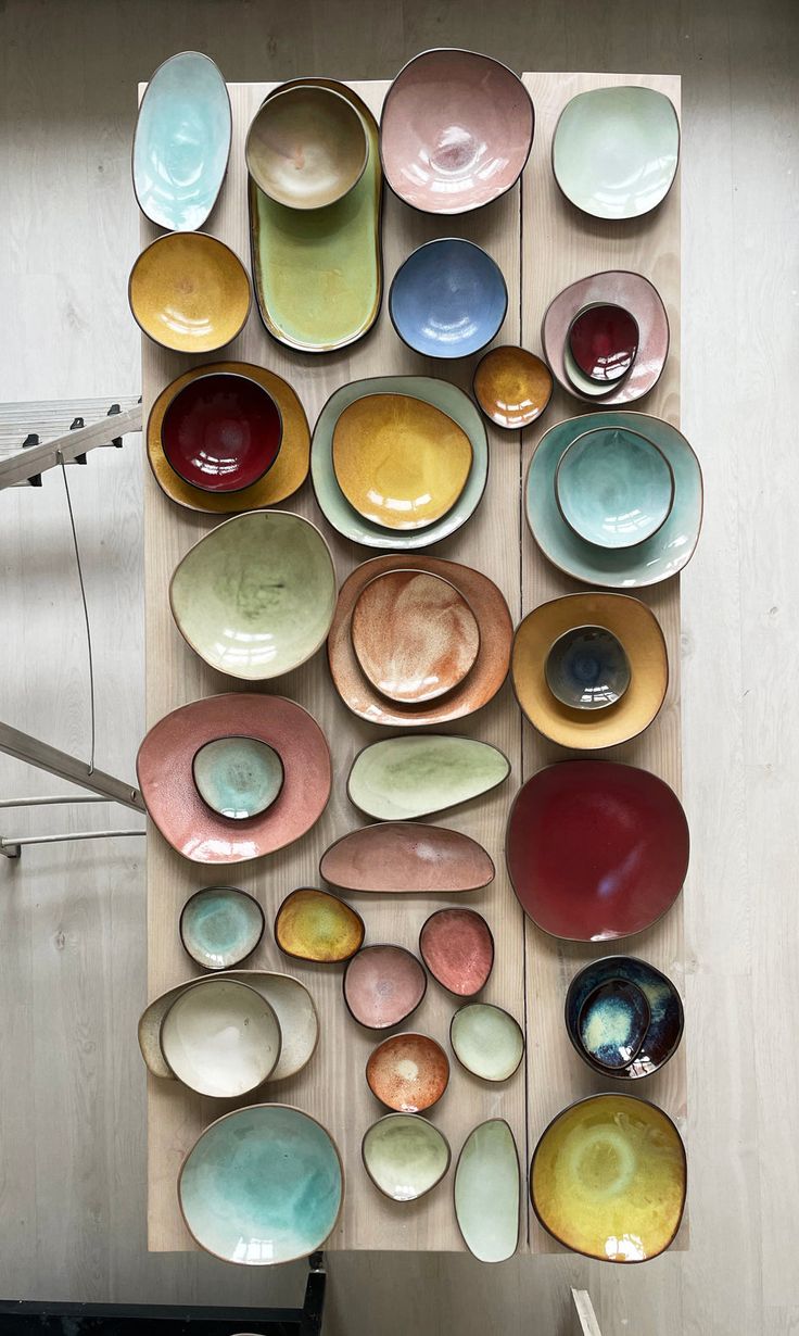 several bowls and plates are arranged on a wooden board with strings hanging from the ceiling