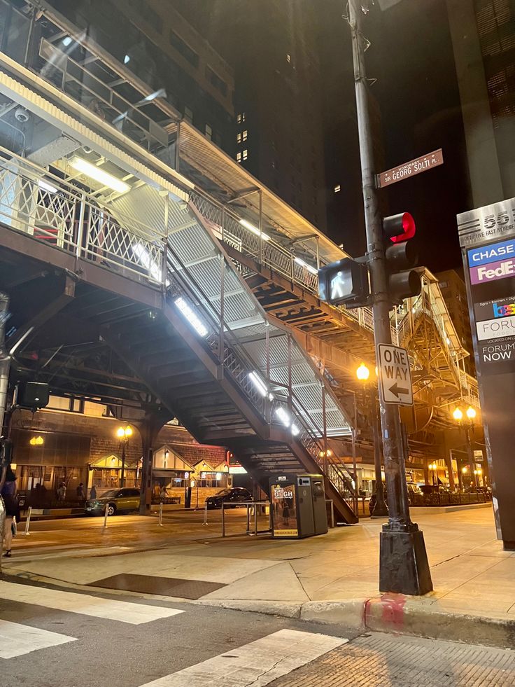 an empty street at night with traffic lights and stairs leading up to the top floor