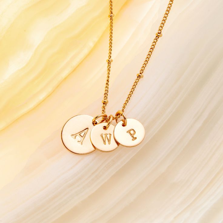 Create a personalized pendant with three initials, expertly crafted from premium gold. Show the world your individual style, and make it personal with this beautiful and meaningful pendant. Make a statement that's uniquely you. How will you show your style? 1/2" and 3/8" gold filled and sterling silver filled disc Hand stamped initial 16" brass satellite chain with 2" extender Lobster claw closure With customization this item is FINAL SALE NOTE - discs DO NOT slide on and off the chain. If you a Gold Pendant Charm Necklace With Name, Elegant Custom Necklace With Initial Pendant, 14k Gold Round Initials Name Necklace, Elegant Yellow Gold Charms For Personalized Gifts, Elegant Initial Necklace With Charms For Mother's Day, Elegant Everyday Nameplate Initial Necklace, Round Yellow Gold Initial Necklace With Charms, Gold Monogram Charm Necklace For Anniversary, Dainty Personalized Custom Necklace With Pendant