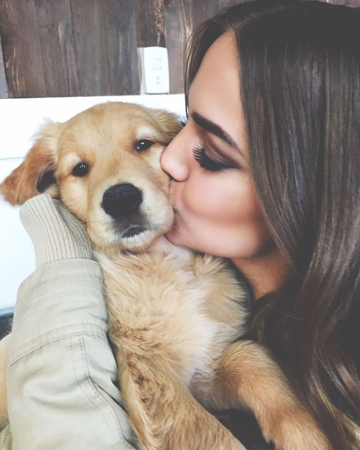 a woman is kissing her dog on the cheek while she holds it up to her face