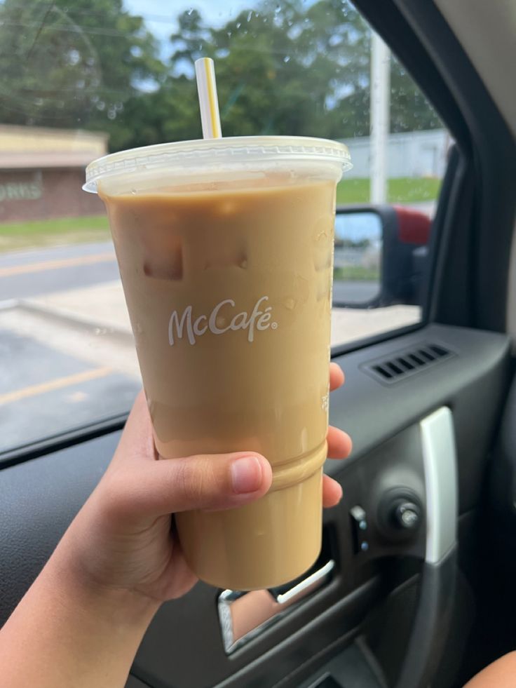 a person holding up a drink in their car