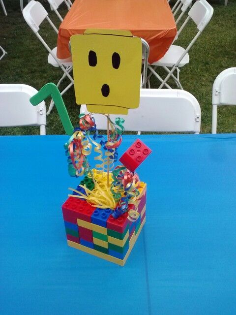 a table topped with a box filled with candy and a face made out of lego blocks