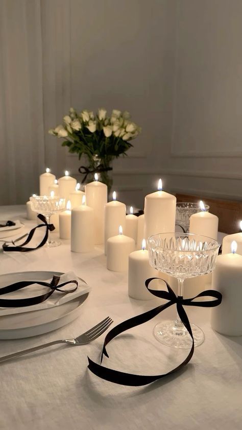 a table topped with lots of white candles next to plates and silver utensils