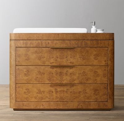 a wooden dresser sitting on top of a hard wood floor next to a white sink