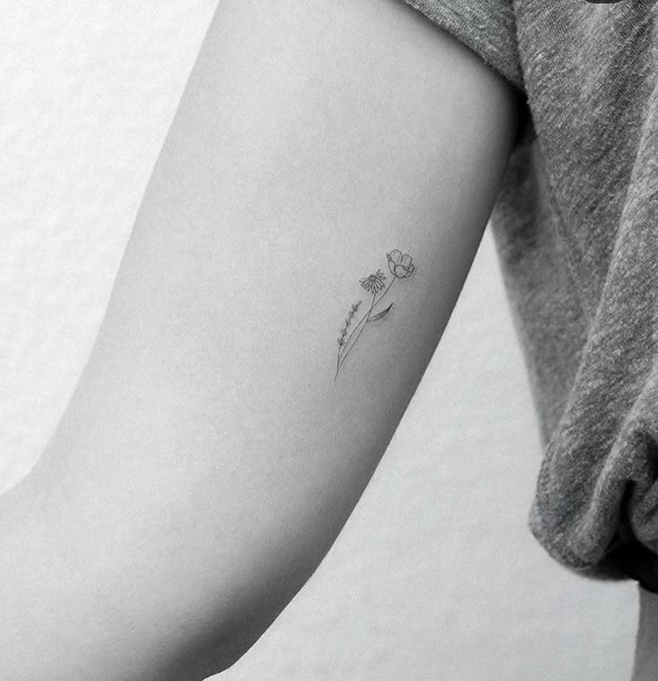 a woman's arm with a single flower tattoo on the left side of her arm