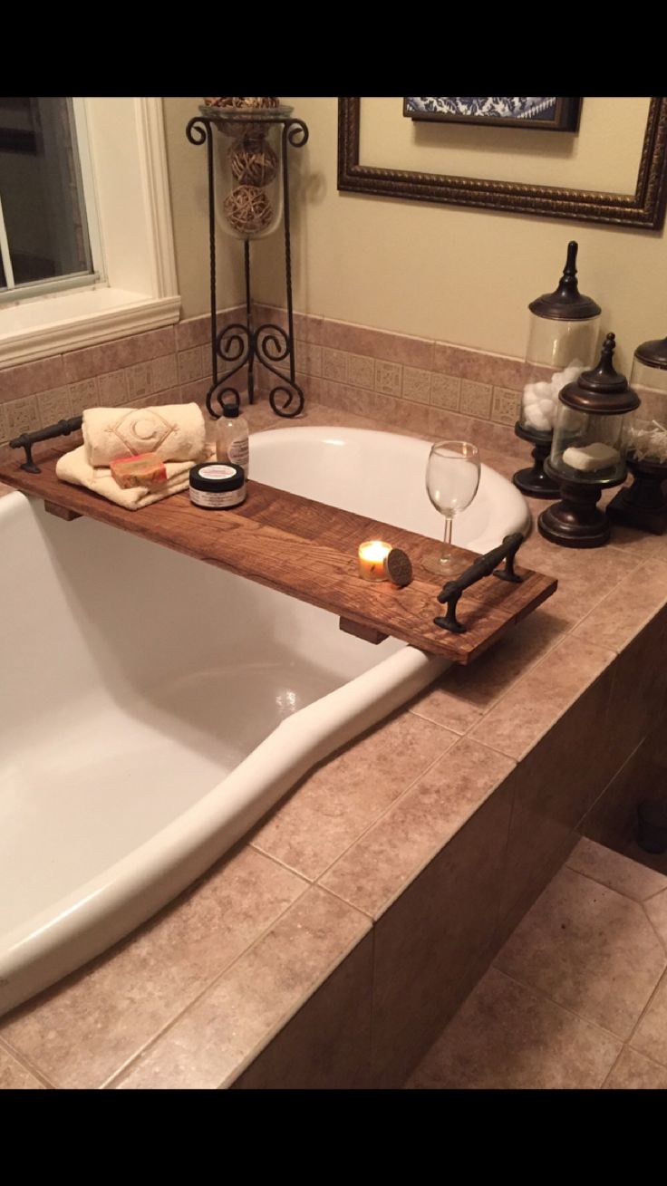 a bathtub with a candle on it in a bathroom next to a mirror and other items