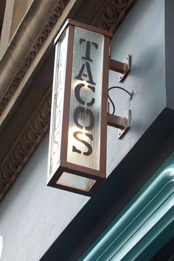 a sign on the side of a building that says taco's