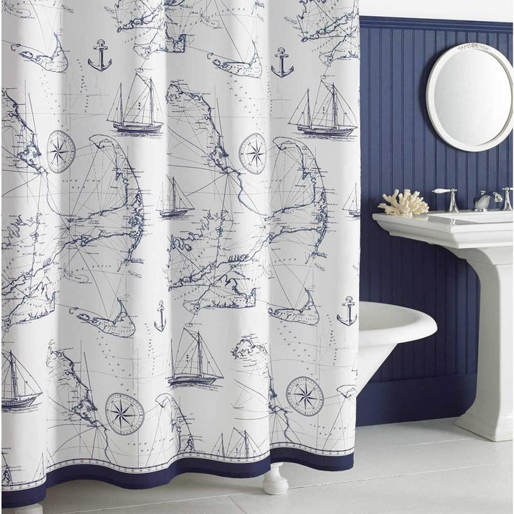 a blue and white bathroom with a shower curtain that has boats on the water in it