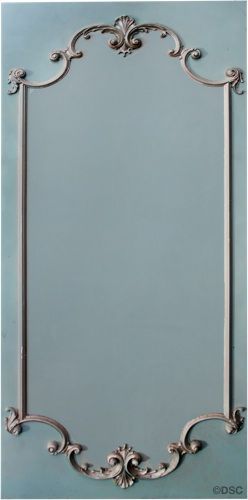 an ornate silver frame against a blue wall with white trimmings and scrolls on the edges