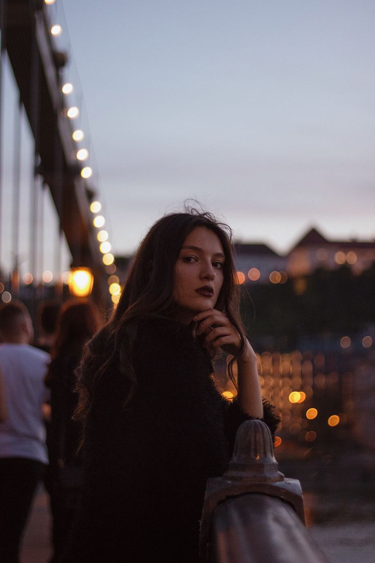 a woman standing next to a bridge at night