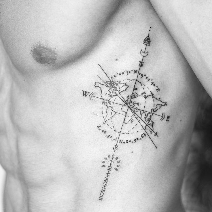 a black and white photo of a man's chest with a compass tattoo on it