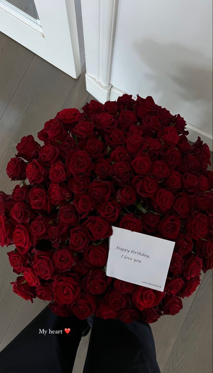 a bouquet of red roses sitting on the floor next to a person's feet