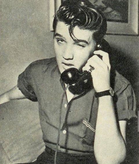 a man sitting at a table talking on a telephone