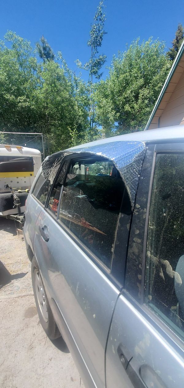 a car parked in front of a house next to a tree filled yard with boats