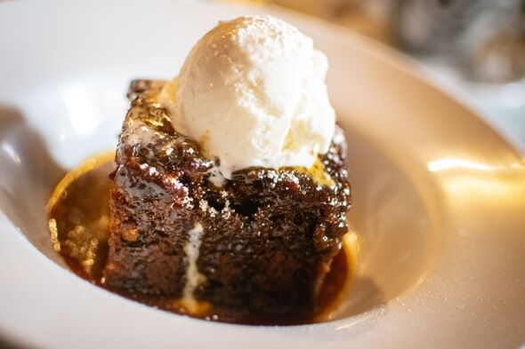 a piece of chocolate cake with ice cream on top in a white bowl sitting on a table