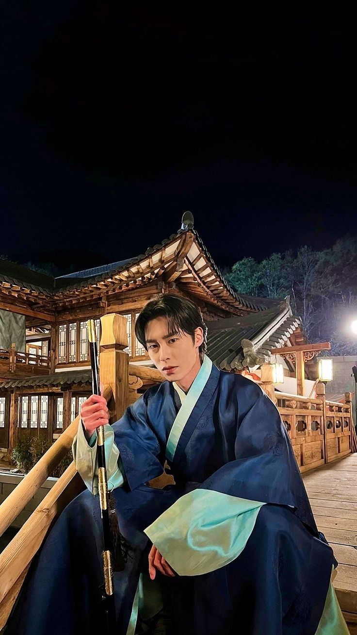 a man dressed in traditional japanese garb sitting on steps holding an umbrella at night