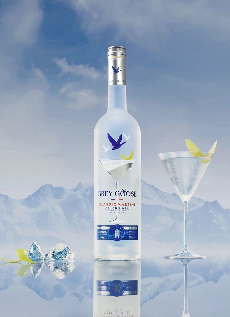 a bottle of grey goose vodka next to a martini glass with a bird on it