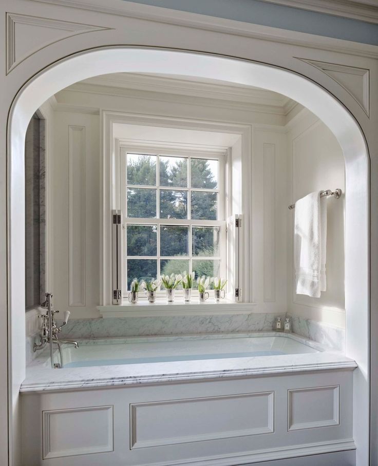 a bath tub sitting under a window in a bathroom