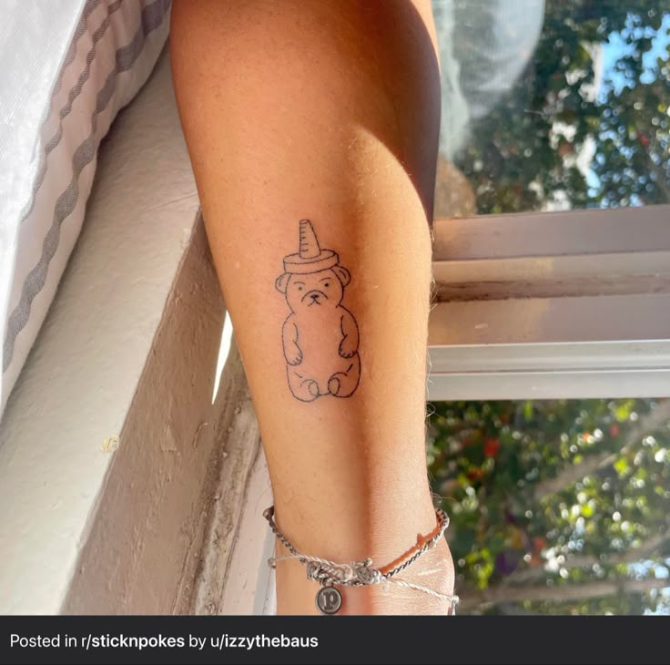 a woman's leg with a tattoo on it and a bear wearing a hat