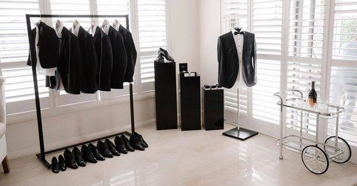 a room filled with lots of black and white clothing hanging on clothes racks next to windows